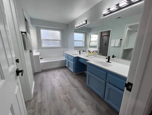A modern bathroom with a bathtub, two sinks, and a large mirror. - Entire 3 BR & 2 BA house for business and family (Modesto)