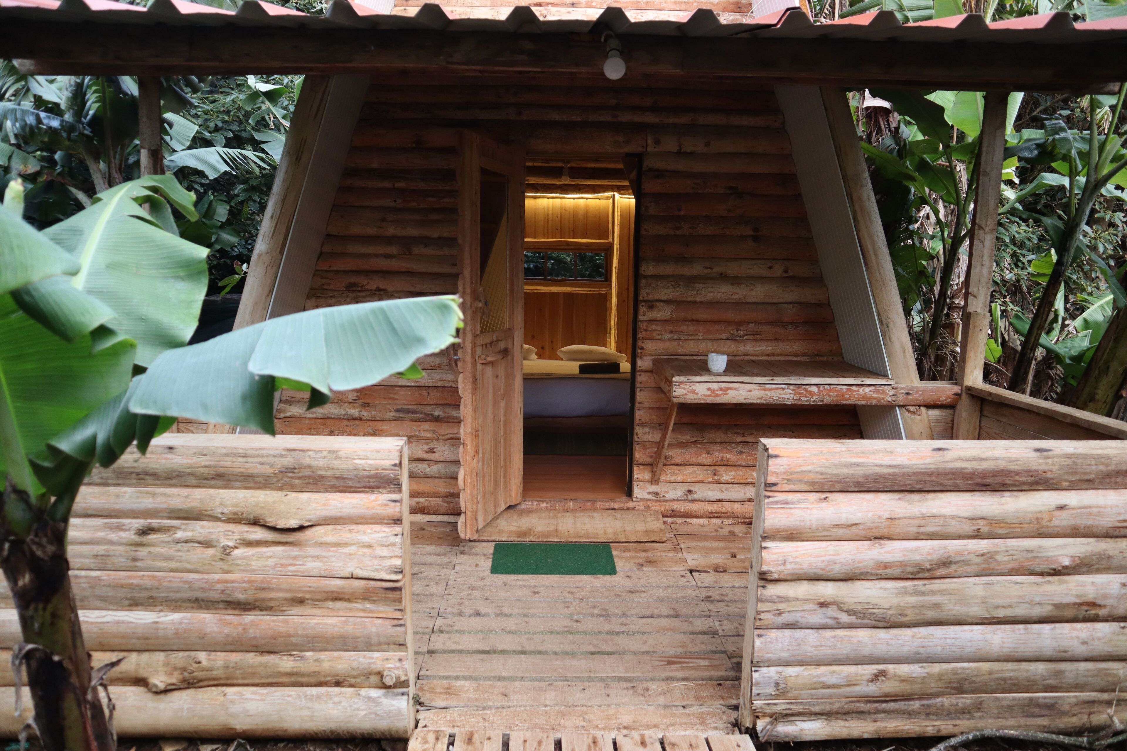 Una cabaña de madera con una escalera de madera que lleva a una cama con un almohadón y una taza sobre una mesa.