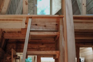 Estructura interior de madera con vigas visibles y techo inclinado, presumiblemente parte de la estructura de un edificio.