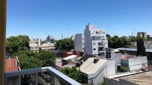 Stadtbild mit modernen Gebäuden, blauem Himmel und umliegender Bepflanzung.