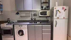 Eine kompakte Küche mit Gasherd, Waschmaschine, Mikrowelle und Kühlschrank.