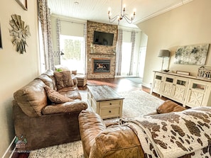 A living room with a leather sofa, a fireplace, a TV, and a cabinet. - Legen-dairy Hideaway, Comfortably Convenient (Park Falls)