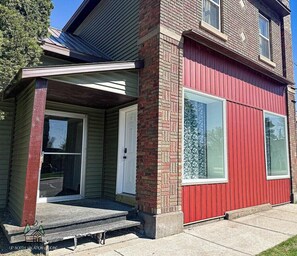 A two-story house with a red exterior, a front porch, and a garage door. - Legen-dairy Hideaway, Comfortably Convenient (Park Falls)