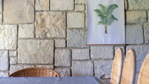 A stone wall with a framed botanical illustration, wicker chairs, and a striped tablecloth. - Luxury Three Bedroom Sea View Villa, Frenchman's Cove Resort (Drapers)