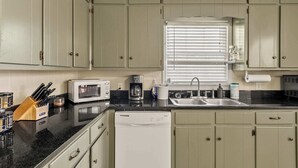 A kitchen with a dishwasher, microwave, sink, and cabinets. - Comfort Cottage (Northport)