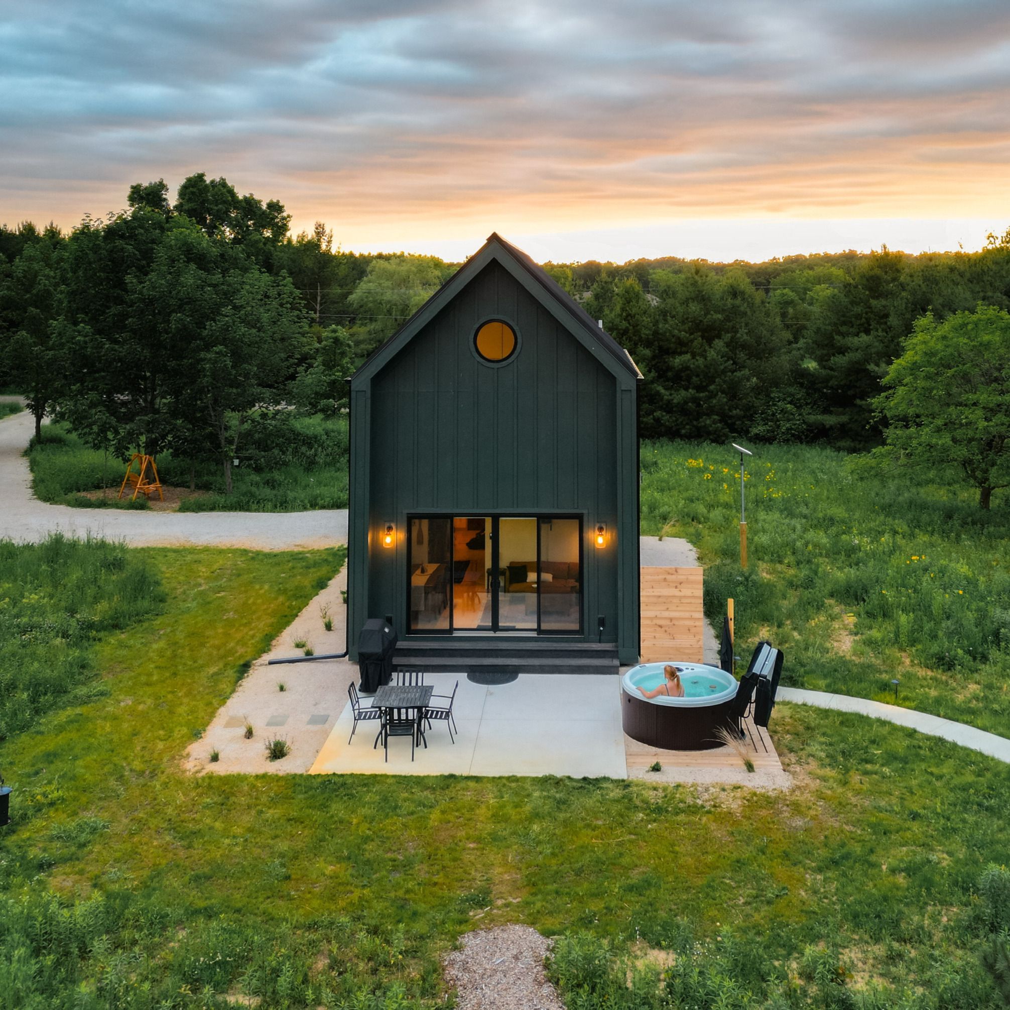 Une maison moderne avec une grande entrée en verre, un patio avec des meubles d’extérieur et un jacuzzi.