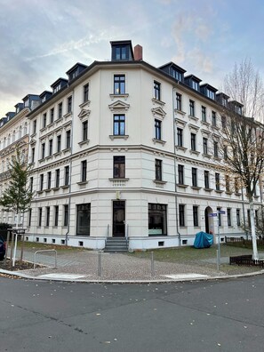 En byggnad med flera våningar i klassisk arkitektonisk stil, med en symmetrisk fasad, stora fönster och en central entré med trappsteg.