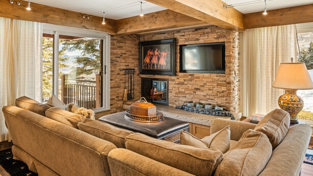 A cozy living room with a stone fireplace, a large flat-screen TV, and a comfortable sofa set. - Direct Ski-in/Ski-out Stonebridge Condo 2 Bedroom Den 3 Bath Deluxe Rated Unit# 600 (Snowmass Village)