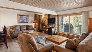 Una sala de estar acogedora con chimenea, sofás de cuero, una mesa de centro de madera y un televisor montado en la pared.