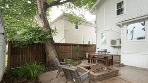 Un jardin avec une terrasse en bois, un barbecue et un espace détente avec des chaises.