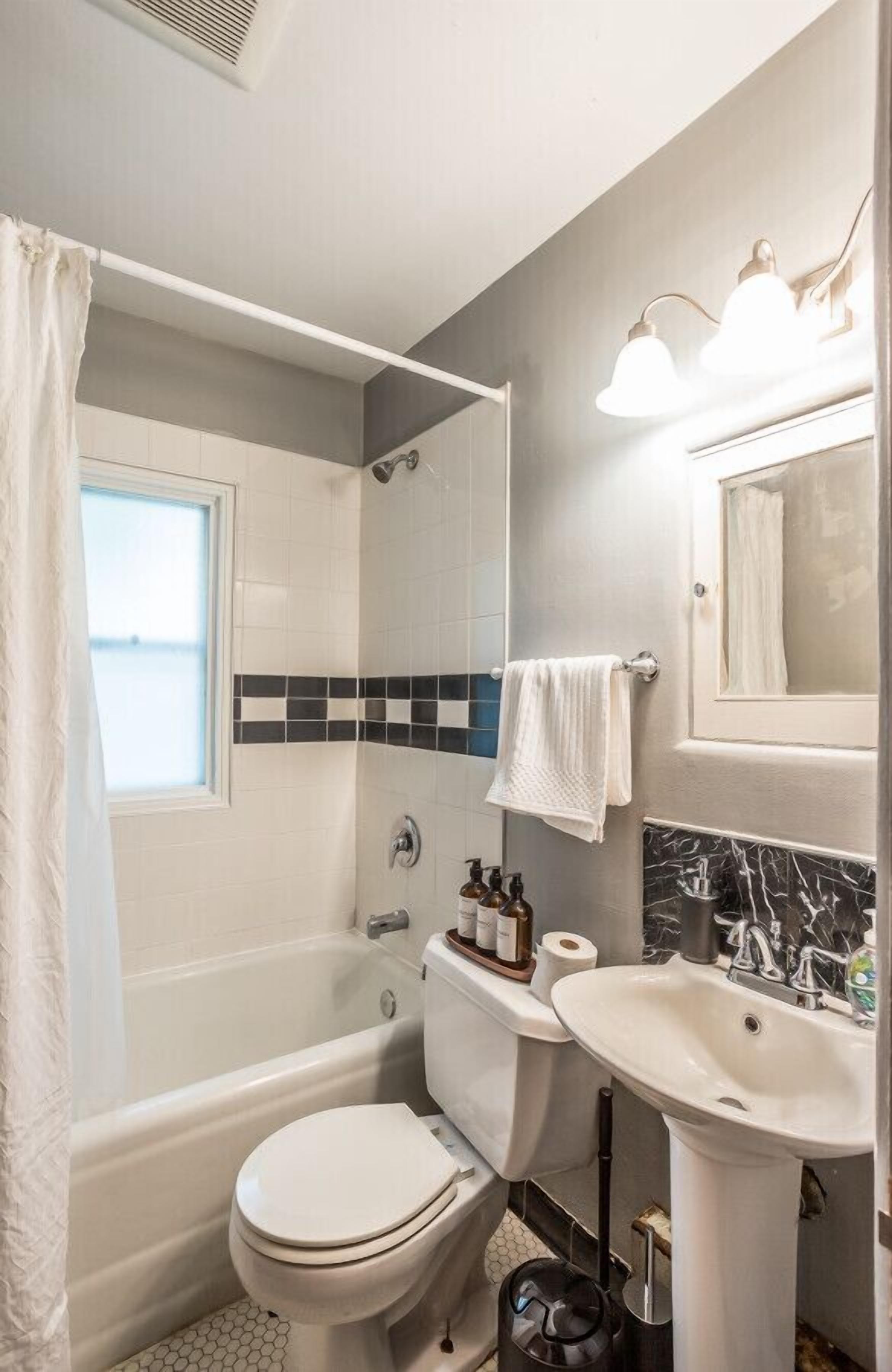 A bathroom with a bathtub, toilet, sink, and a shower area.
