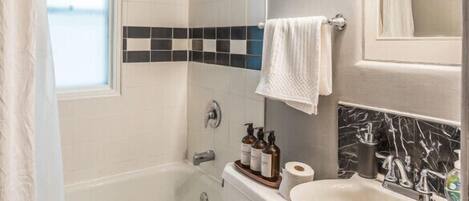 A bathroom with a bathtub, toilet, sink, and a shower area.