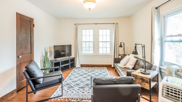 A living room with a sofa, a chair, a TV, a lamp, and a heater.