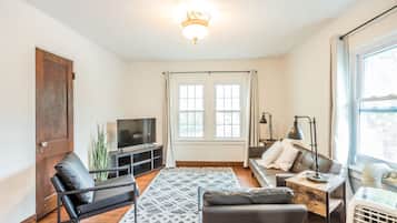 A living room with a sofa, a chair, a TV, a lamp, and a heater.