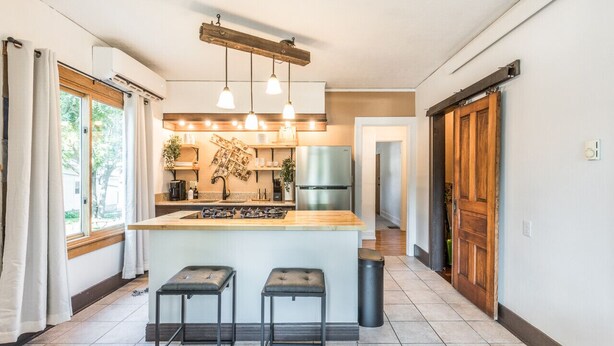 A modern kitchen with a central island, pendant lighting, and a view to the dining area.