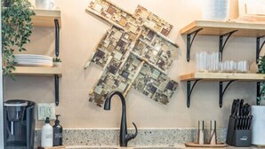A kitchen with dark wood cabinets, a granite countertop, a hanging tile backsplash, and a coffee maker.