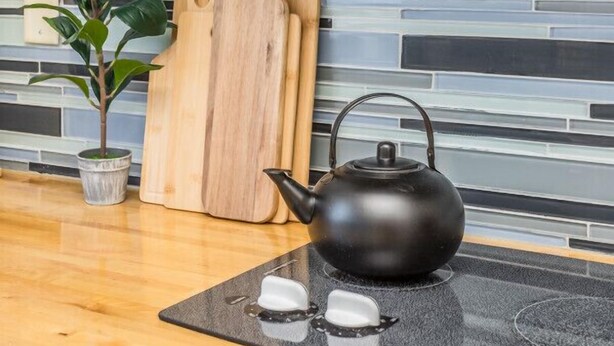 Een keuken met een modern design, met een magnetron, waterkoker en houten snijplanken.