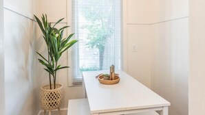 Een kleine ruimte met een witte tafel, een bankje en een hanglamp.