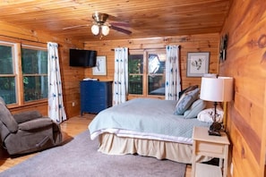 A cozy cabin bedroom with a bed, a TV, a desk, and a chair. - Charley's Cabin - Mountain Vacation. Beautiful log cabin on almost 3 acres. (Waynesville)