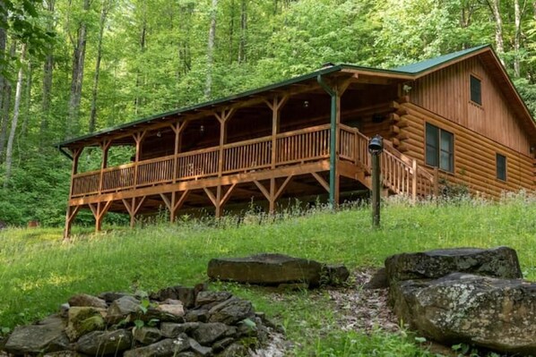 Eine Blockhütte mit überdachter Veranda und einem Feuerkorb aus Stein.