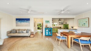 A spacious living area with a sofa, dining table, and chairs, a kitchen with green cabinets, and a ceiling fan. - MacMasters Malibu - Lakefront by HolidayCo. (MACMASTERS BEACH)