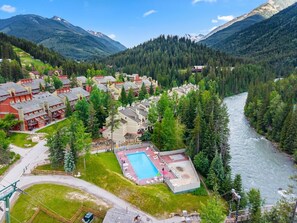 A resort with a swimming pool, multiple buildings, and a river.