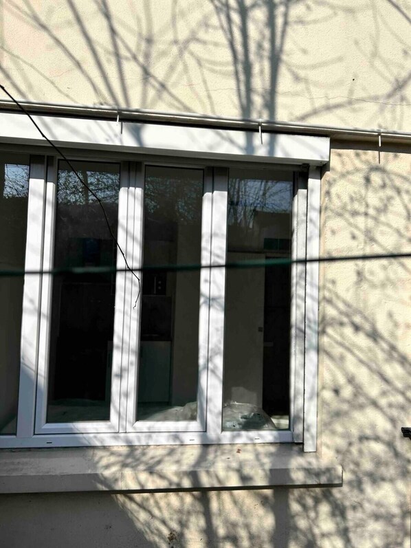 A window with a white frame and a view of a tree outside. - Studio Centre Ville Massy (Massy)