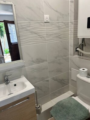 A bathroom with a sink, mirror, toilet, and towel rack. - Studio Centre Ville Massy (Massy)