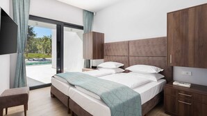 A modern hotel room with a large bed, a desk, and a TV. - Luxury Villa Mauve with Pool (Režanci)