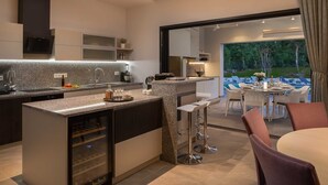 A modern kitchen with granite countertops, a built-in wine cooler, and a bar area with stools. - Luxury Villa Mauve with Pool (Režanci)
