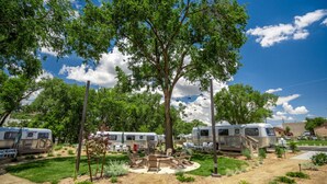 A campsite with RVs, a fire pit, and a picnic table surrounded by trees.
