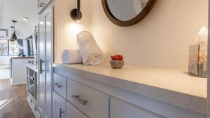 A modern bathroom with a large mirror, white cabinets, and a marble countertop.