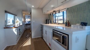 A modern kitchen with a coffee bar, stainless steel appliances, and a view through the window.