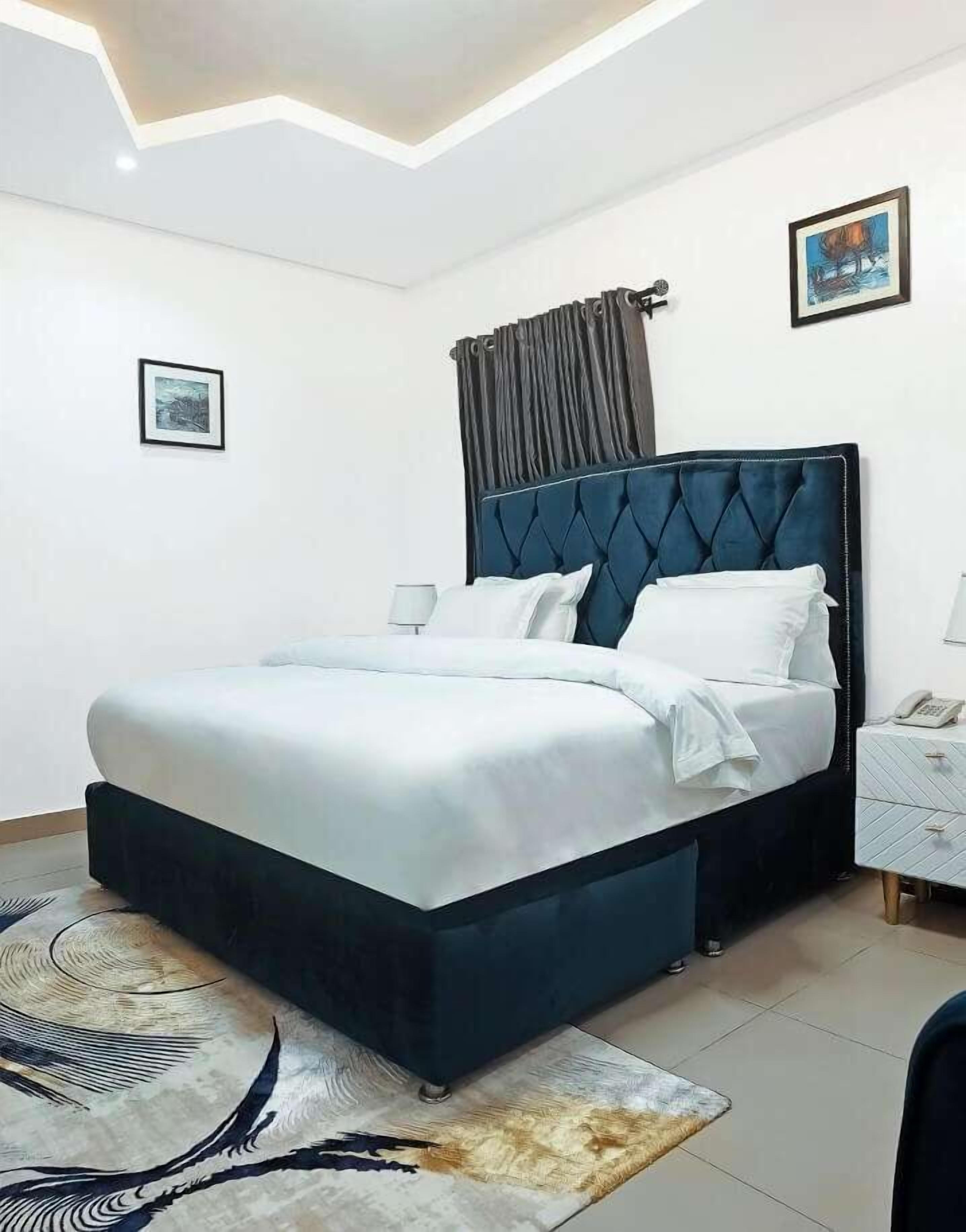 A modern bedroom with a large bed, a nightstand, a lamp, and a framed picture on the wall.