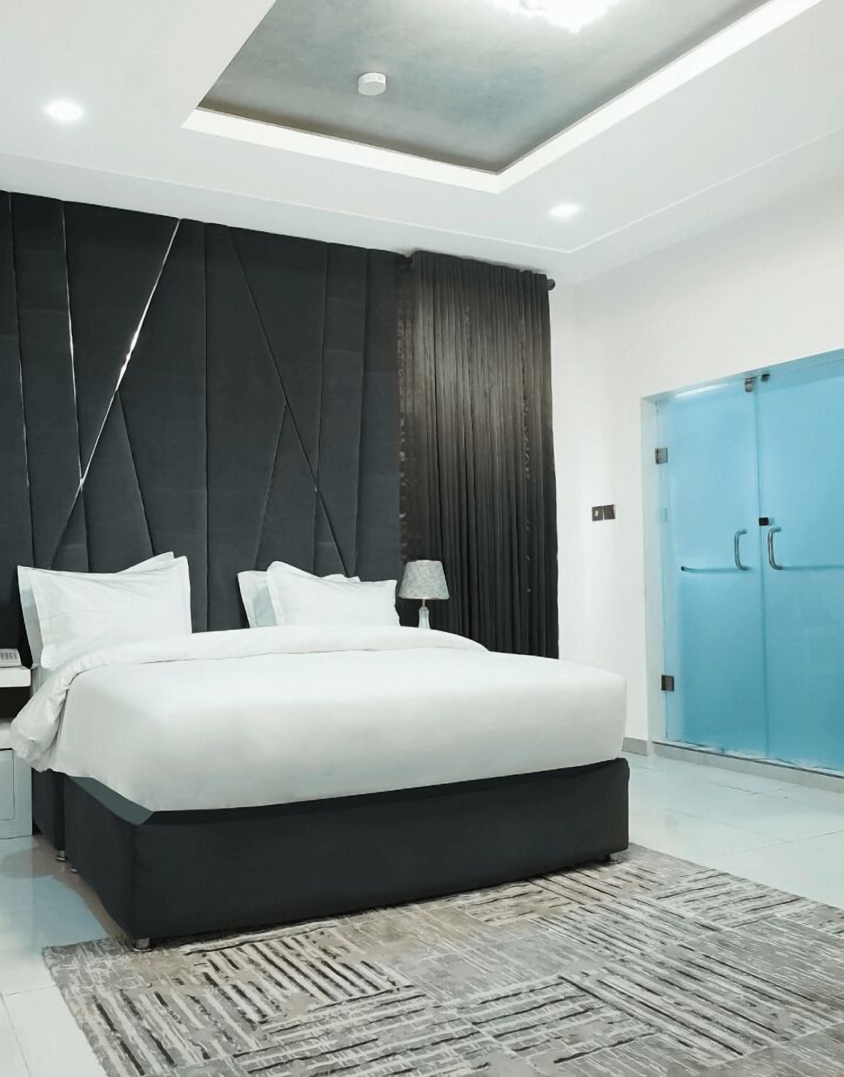 Une chambre moderne avec un grand lit, une tête de lit sombre et une armoire bleue.