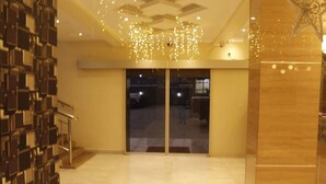 A hotel lobby with a modern design, featuring a glass door entrance, a staircase, and a decorative ceiling light fixture.