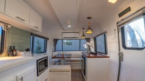 Uma cozinha compacta com bancada para café, forno embutido e área de jantar com banco.