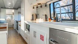 A modern kitchen with white cabinetry, stainless steel appliances, and a window providing a view of the outdoors.