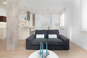 Una sala moderna con un sofá gris, una mesa de centro blanca y velas azul turquesa.