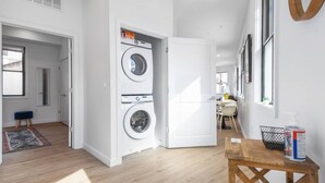 A laundry room with two washing machines, a wooden bench, and a bottle of hand sanitizer. - ✮Unique 1BR | Walk to NJPAC/NJPENN | 30min to NYC✮ (Newark)