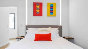 A modern hotel room with a large bed, a grey headboard, and two nightstands. There are two artworks on the wall above the bed. - ✮Unique 1BR | Walk to NJPAC/NJPENN | 30min to NYC✮ (Newark)