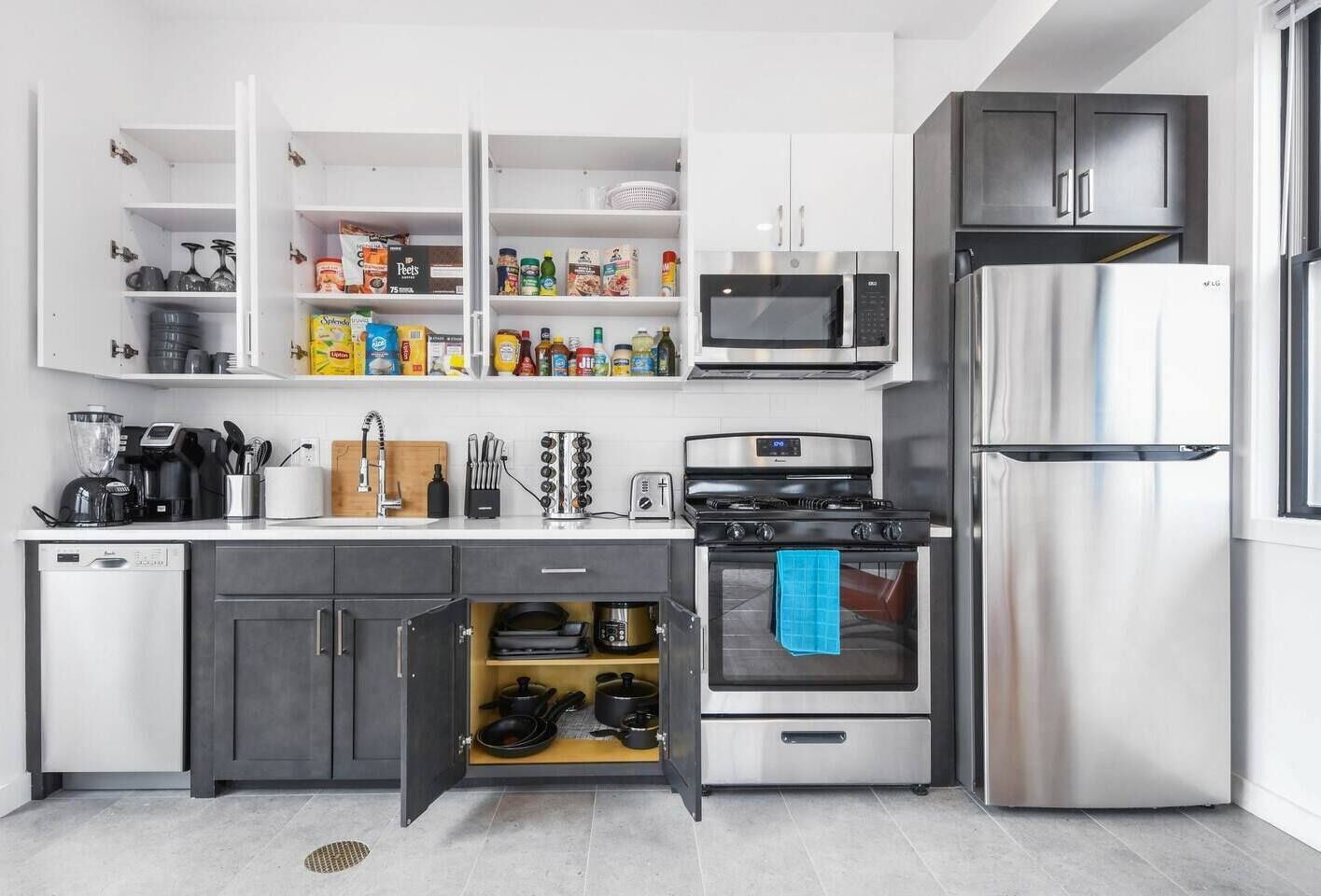 A modern kitchen with white cabinetry, a built-in oven, a microwave, and a stainless steel refrigerator.