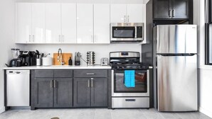 A modern kitchen with white and dark gray cabinets, a stainless steel refrigerator, a microwave, a stove, and a dishwasher. - ✮Unique 1BR | Walk to NJPAC/NJPENN | 30min to NYC✮ (Newark)