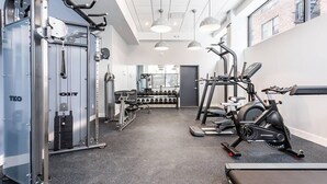 Une salle de sport moderne équipée de divers appareils d’exercice, notamment une machine de musculation, des tapis de course et un vélo elliptique.
