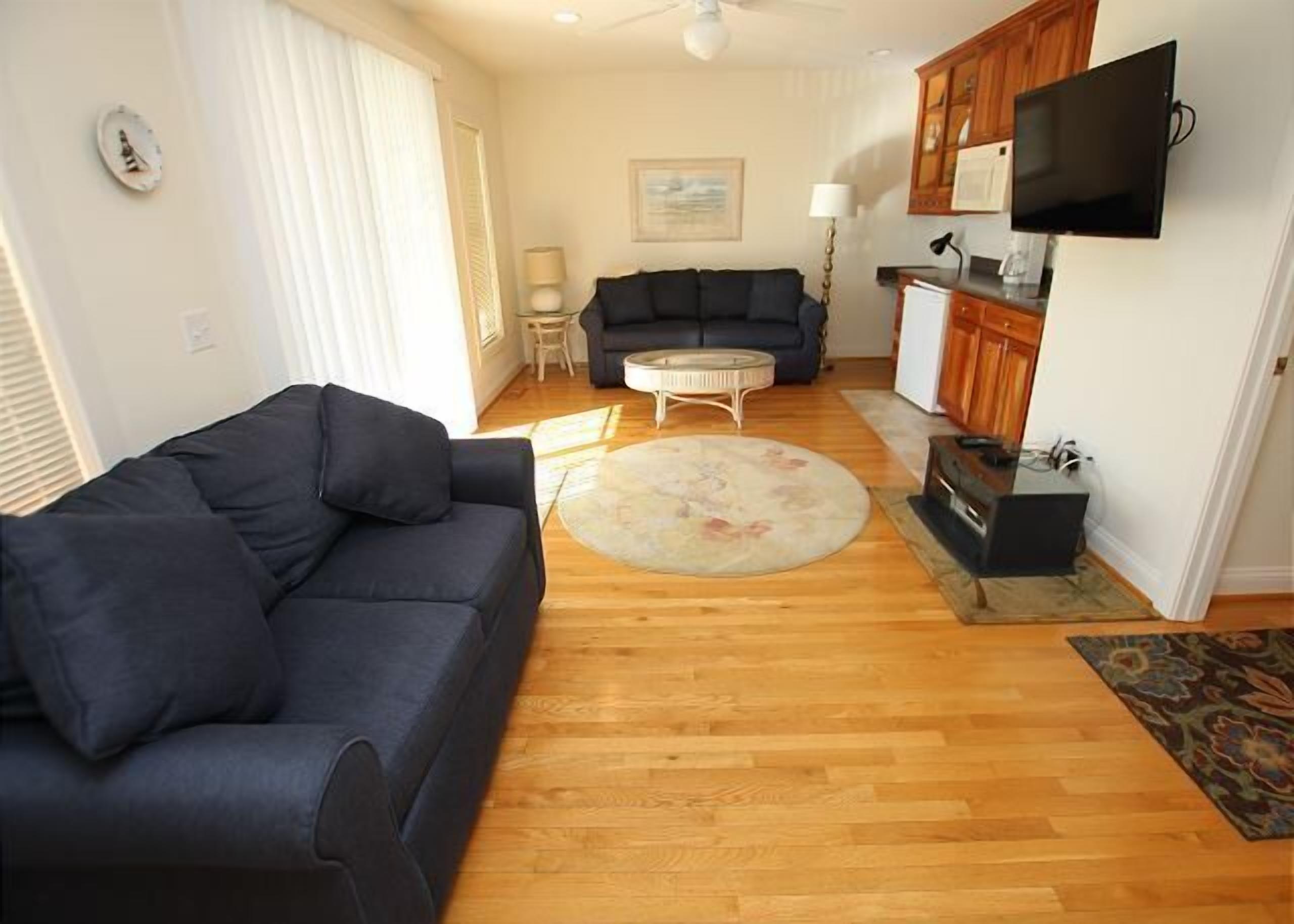 A living room with a dark blue sofa, a round coffee table, and a patterned rug.