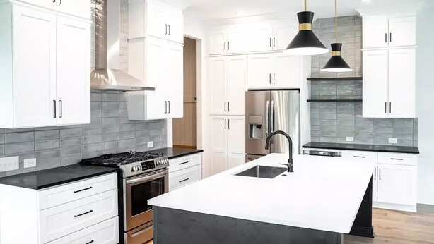 A modern kitchen with white cabinets, a black countertop, a stainless steel stove, and a black pendant light. - Newly Built Modern Home In CLT! Great Location! (Charlotte)