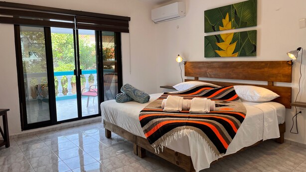 Une chambre à coucher avec un lit en bois, une grande fenêtre et un ventilateur de plafond.