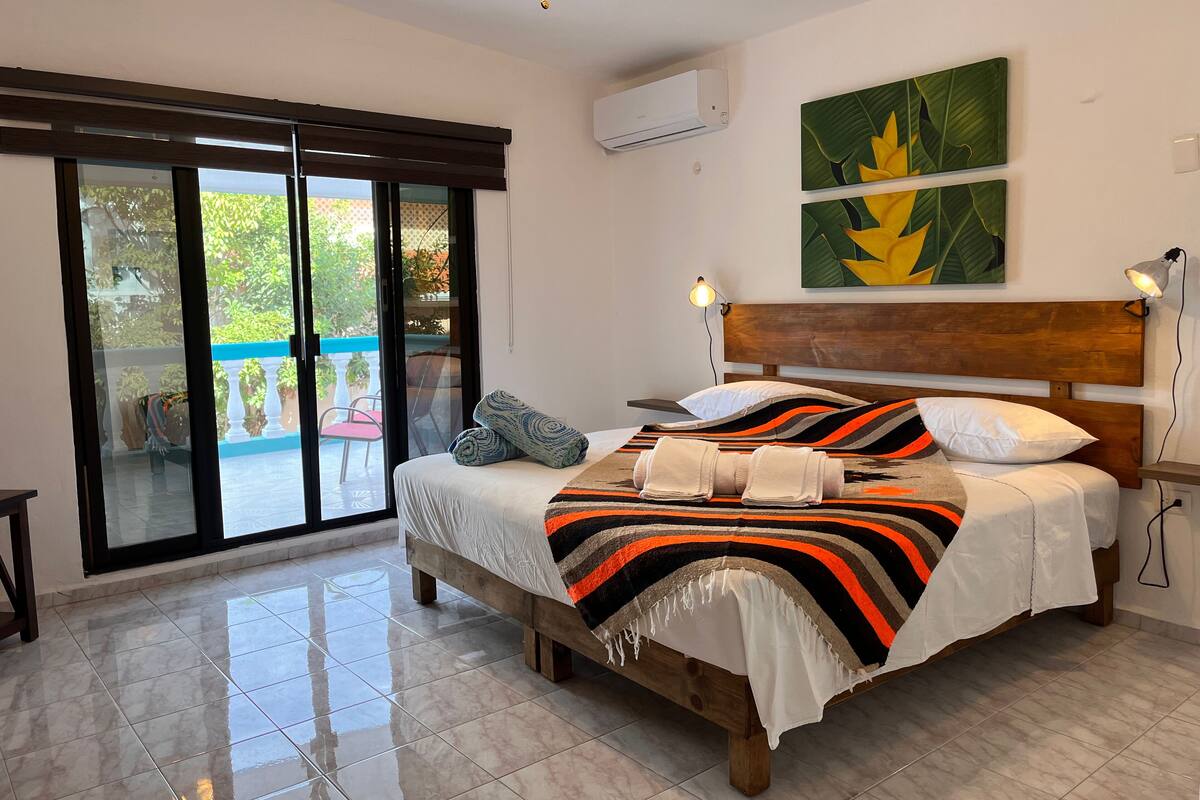 Ein Schlafzimmer mit einem hölzernen Bett, einem großen Fenster und einem Deckenventilator.