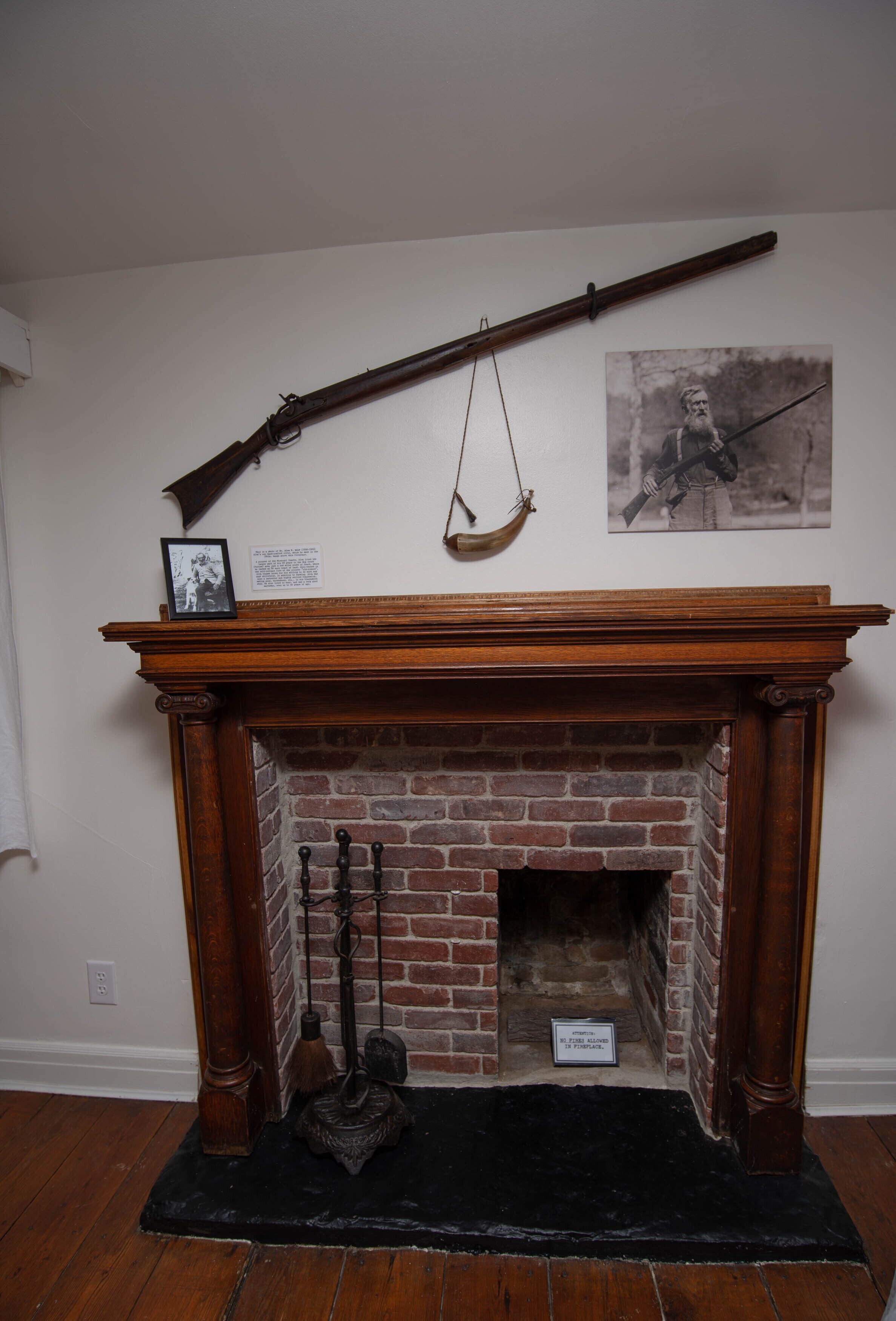 A fireplace with a wooden mantel, a hanging coat rack, and a framed picture above it.