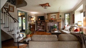 Una sala de estar amplia con chimenea, una escalera y un rincón de descanso acogedor.